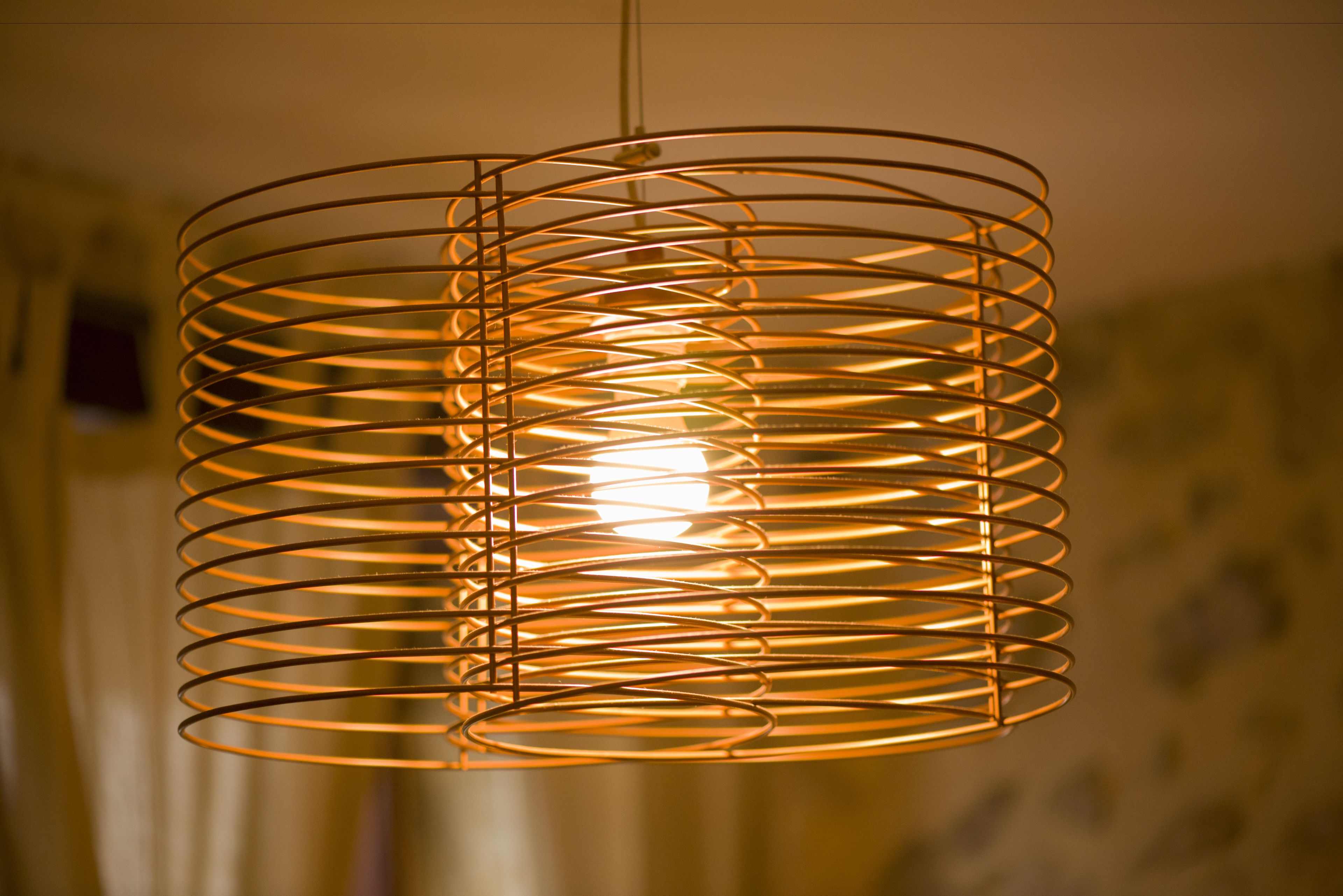 Una lámpara colgante de metal con forma espiral y una luz cálida.
