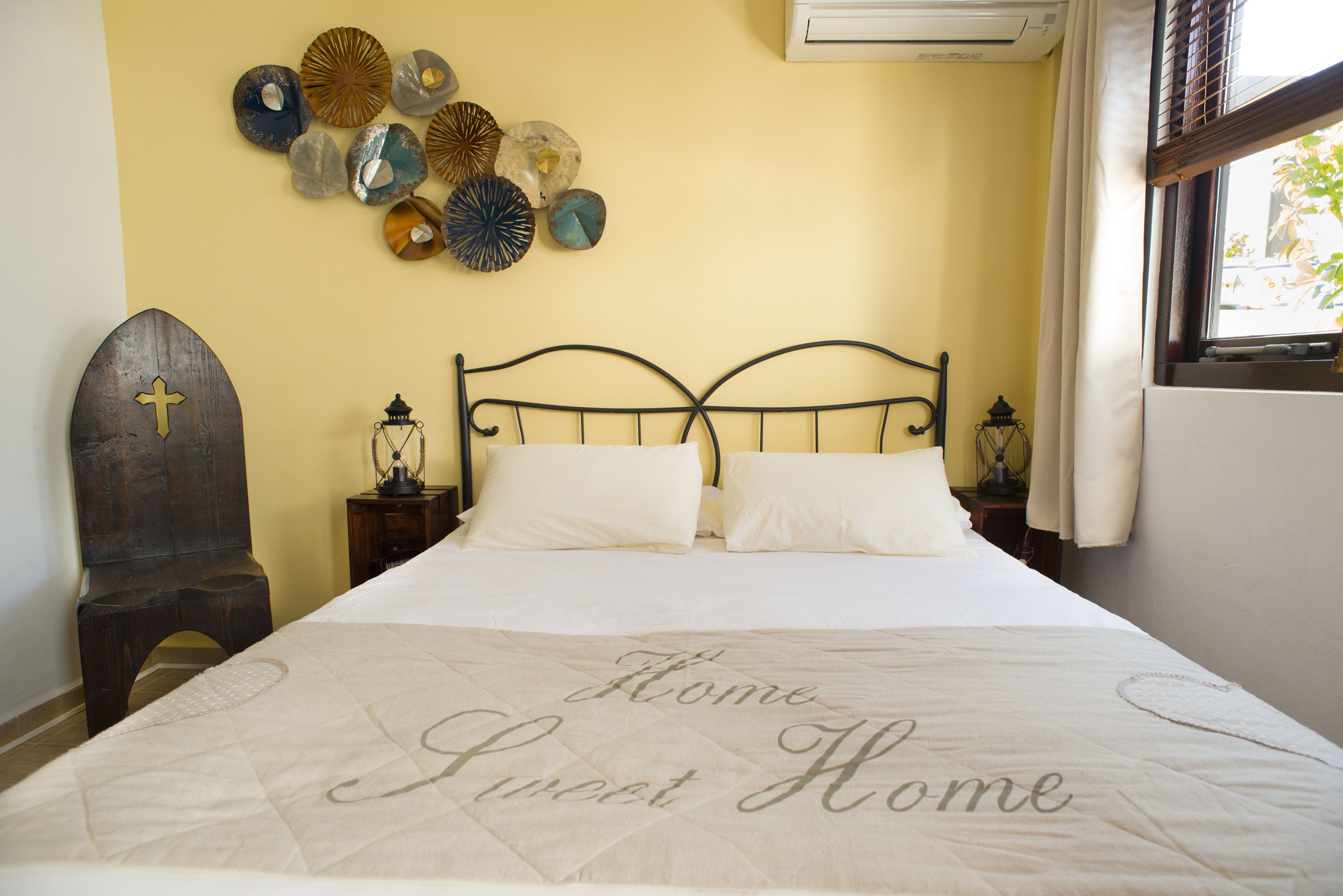 Una cama bien tendida con un colcha que dice 'Home Sweet Home' en un dormitorio de diseño sencillo y limpio.