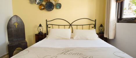 A neatly made bed with a quilt that reads "Home Sweet Home" in a bedroom with a simple, clean design.