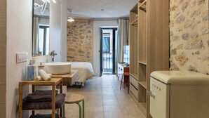 Una habitación de hotel compacta con baño, una cama, un armario de madera y una pequeña mesa con toallas.