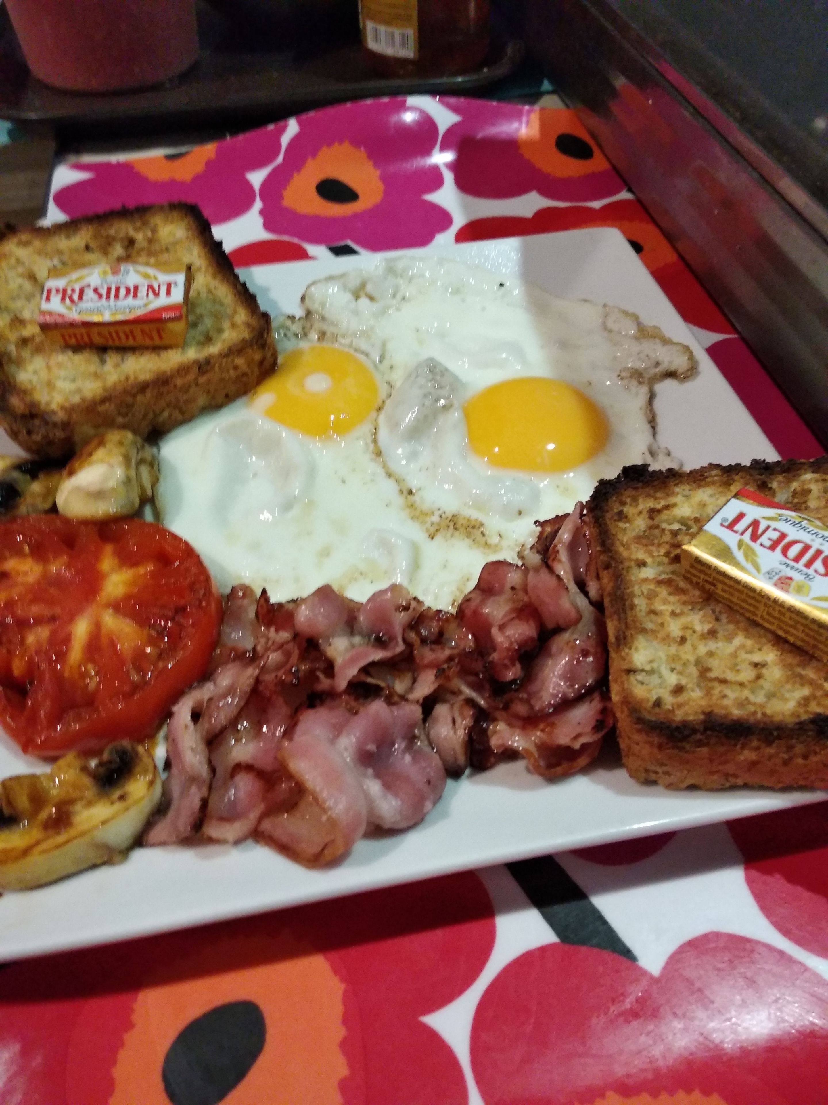 A breakfast plate with eggs, bacon, tomatoes, and toast.