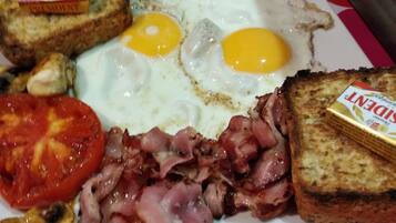 Un plato de desayuno con huevos, tocino, tomates y tostadas.