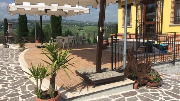A patio area with outdoor furniture, a large umbrella, and potted plants. - Agriturismo I Tre Ulivi (Paternopoli)