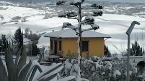 A yellow building with a snow-covered landscape in the background. - Agriturismo I Tre Ulivi (Paternopoli)