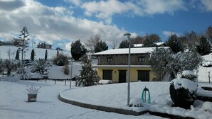 A snow-covered landscape with a stone building, a circular driveway, and a few trees. - Agriturismo I Tre Ulivi (Paternopoli)