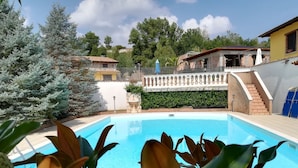 A swimming pool surrounded by greenery, with a stone wall and a staircase leading to a building. - Agriturismo I Tre Ulivi (Paternopoli)