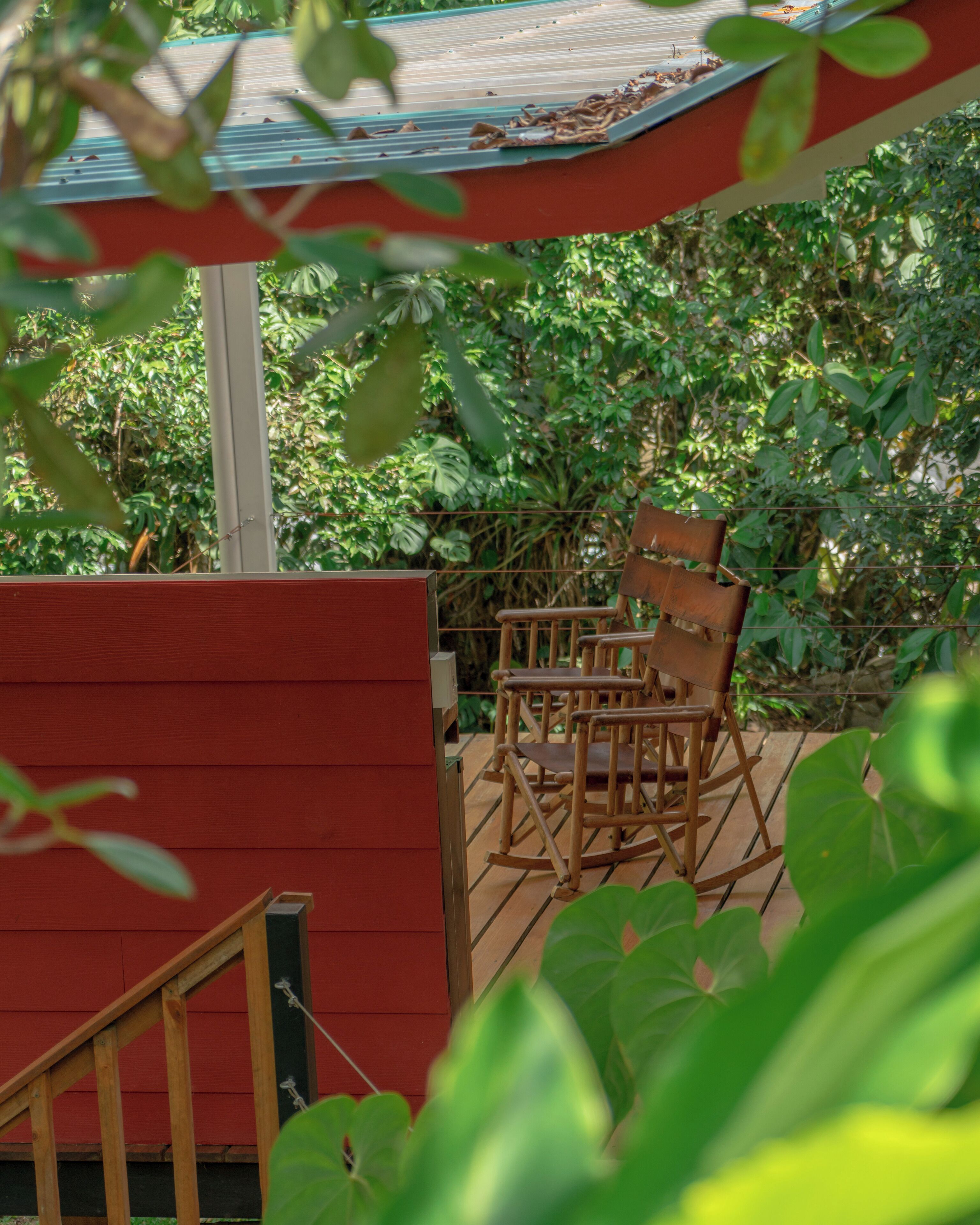 A wooden deck with a rocking chair and a red wall.