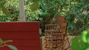 A wooden deck with a rocking chair and a red wall.