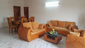 A living room with wicker furniture, a dining table, and chairs.