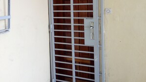 A metal door with horizontal bars, a small light above it, and a lock on the right side.