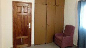A room with a wooden door, a large wardrobe, and a red chair.