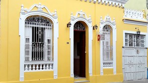 A yellow building with ornate white window frames and a gated entrance. - Hostal D' Cordero (Santa Clara)
