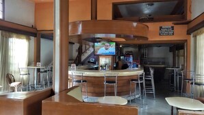 A bar area with a TV screen, bar stools, and a warning sign about alcohol. - Sagas Hotel Ltd (Nairobi)
