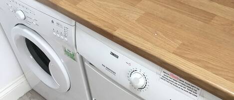 A front-loading washing machine with a wooden countertop above it.