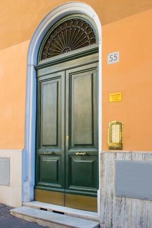 A green double door with a decorative window above it, a number '55' sign, and a small plaque on the wall. - B&B Laurus Colosseo (Rome)