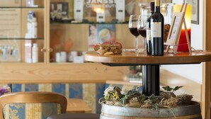 Eine Bar mit Holztresen, Weinflaschen, Gläsern und einer kleinen Auswahl an Snacks.