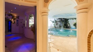 Eine Hotelhalle mit Poolbereich, inklusive Wasserspiel und Wandgemälde.