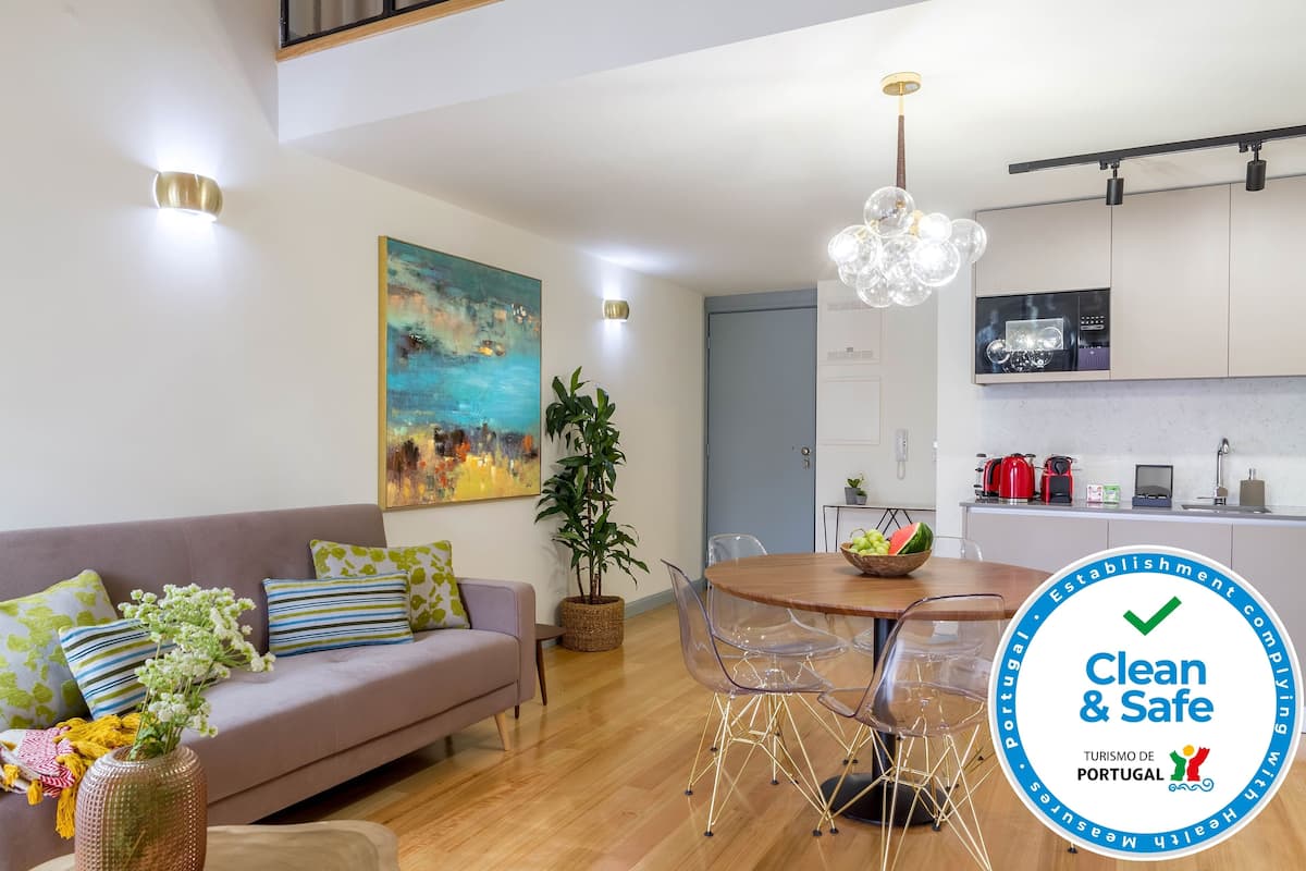 A modern living room with a sofa, dining table, and kitchen area.