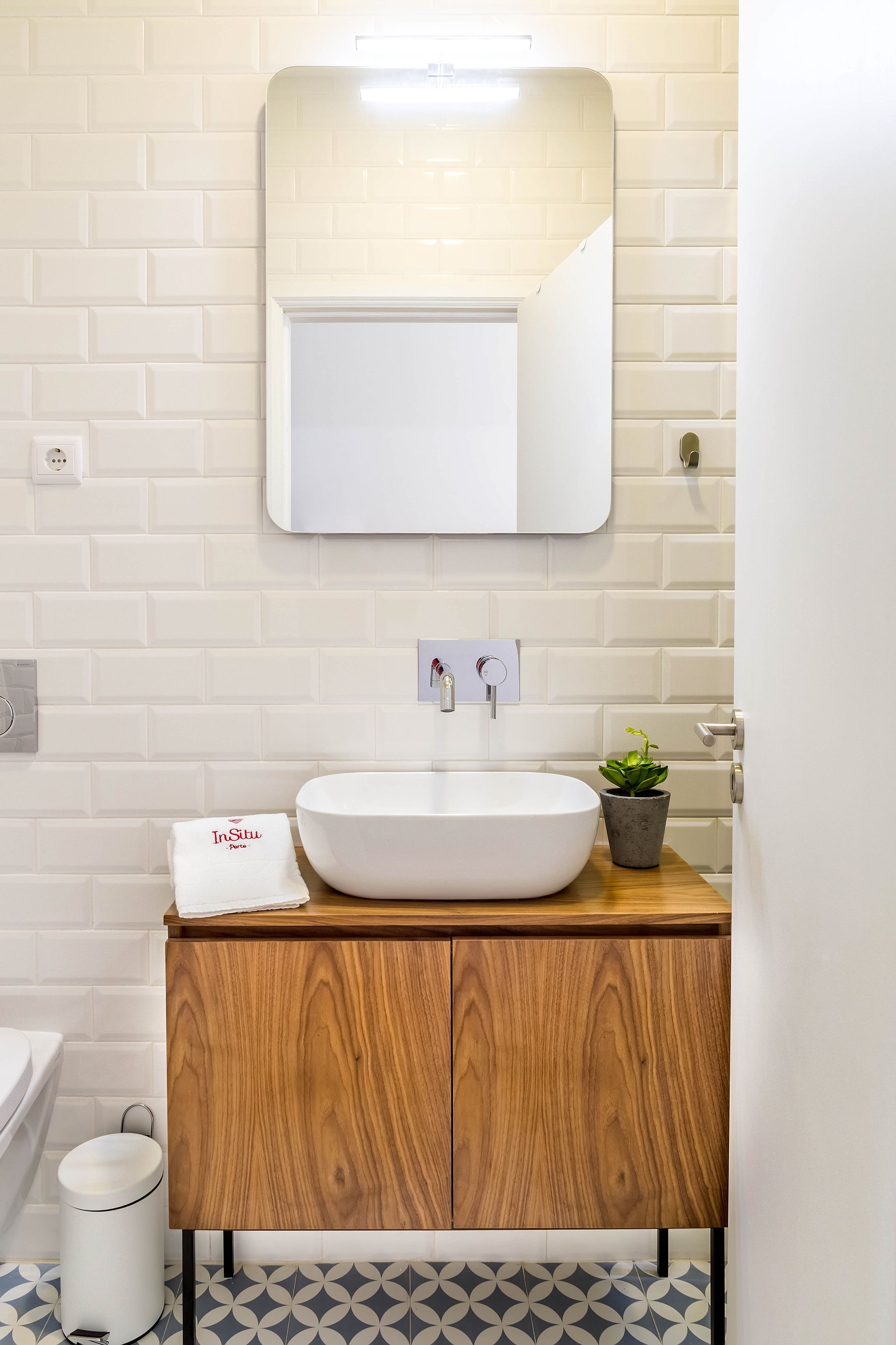 A bathroom with a white sink, wooden cabinet, and a potted plant.