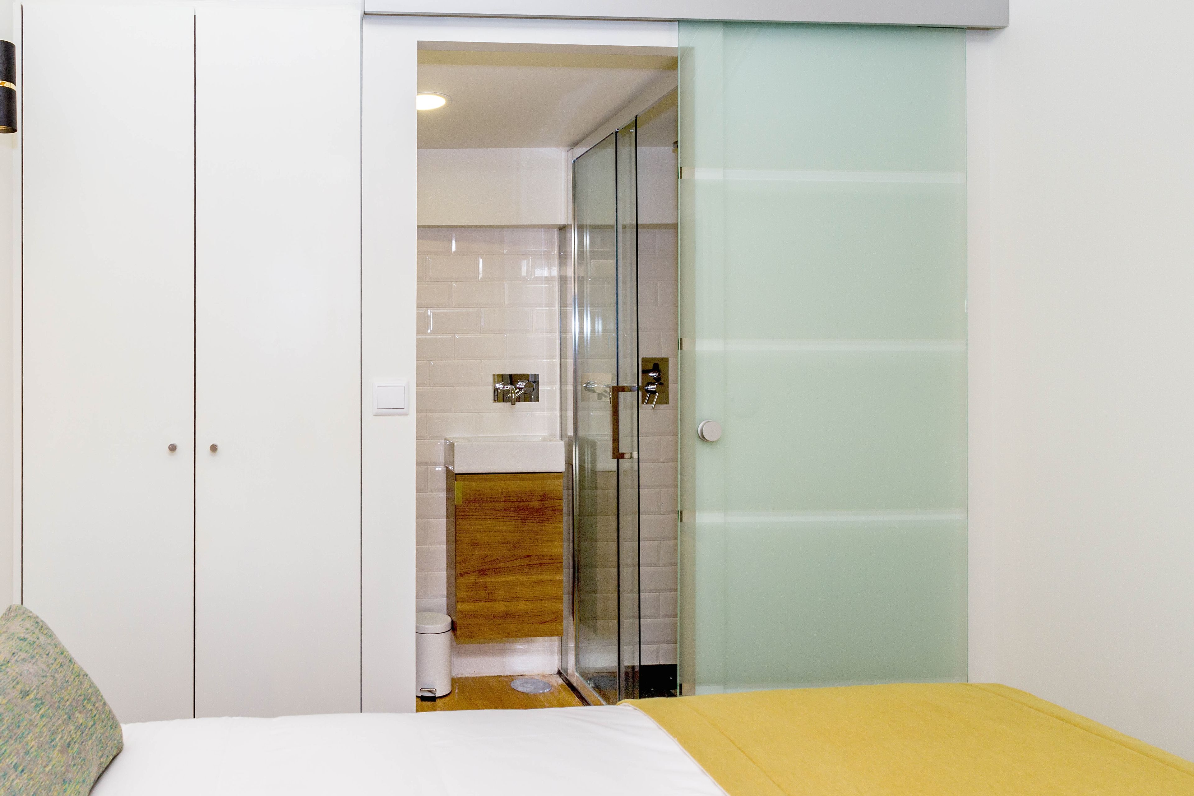 A bedroom with a bed, a wardrobe, and a bathroom with a shower and toilet.