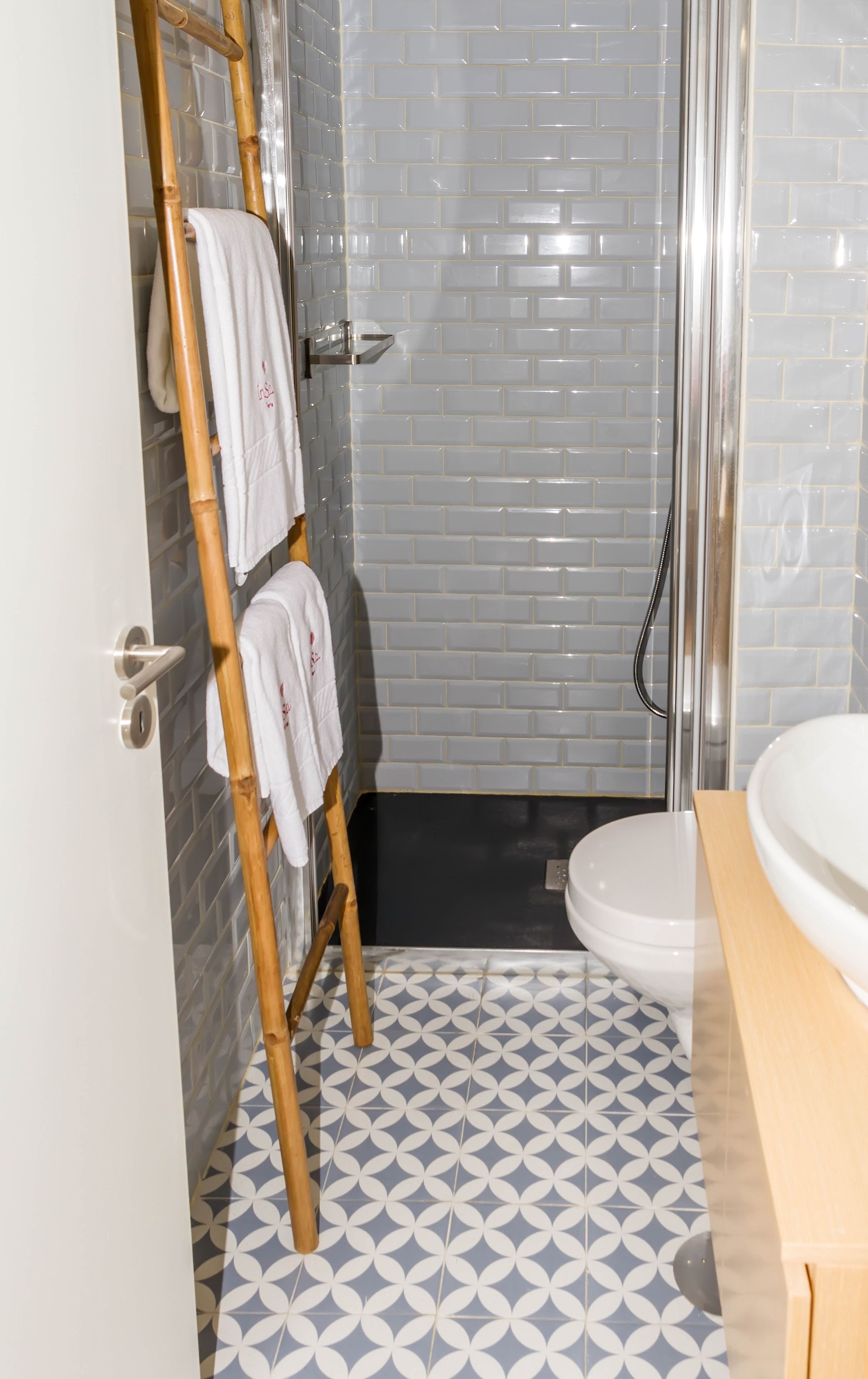 Ein Badezimmer mit Dusche, Toilette und einem Handtuchhalter mit Handtüchern.