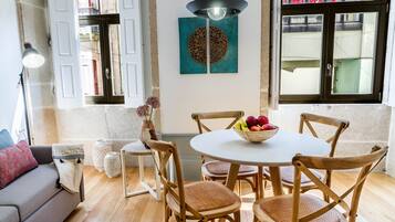 Un comedor con una mesa redonda, sillas de madera y un frutero.