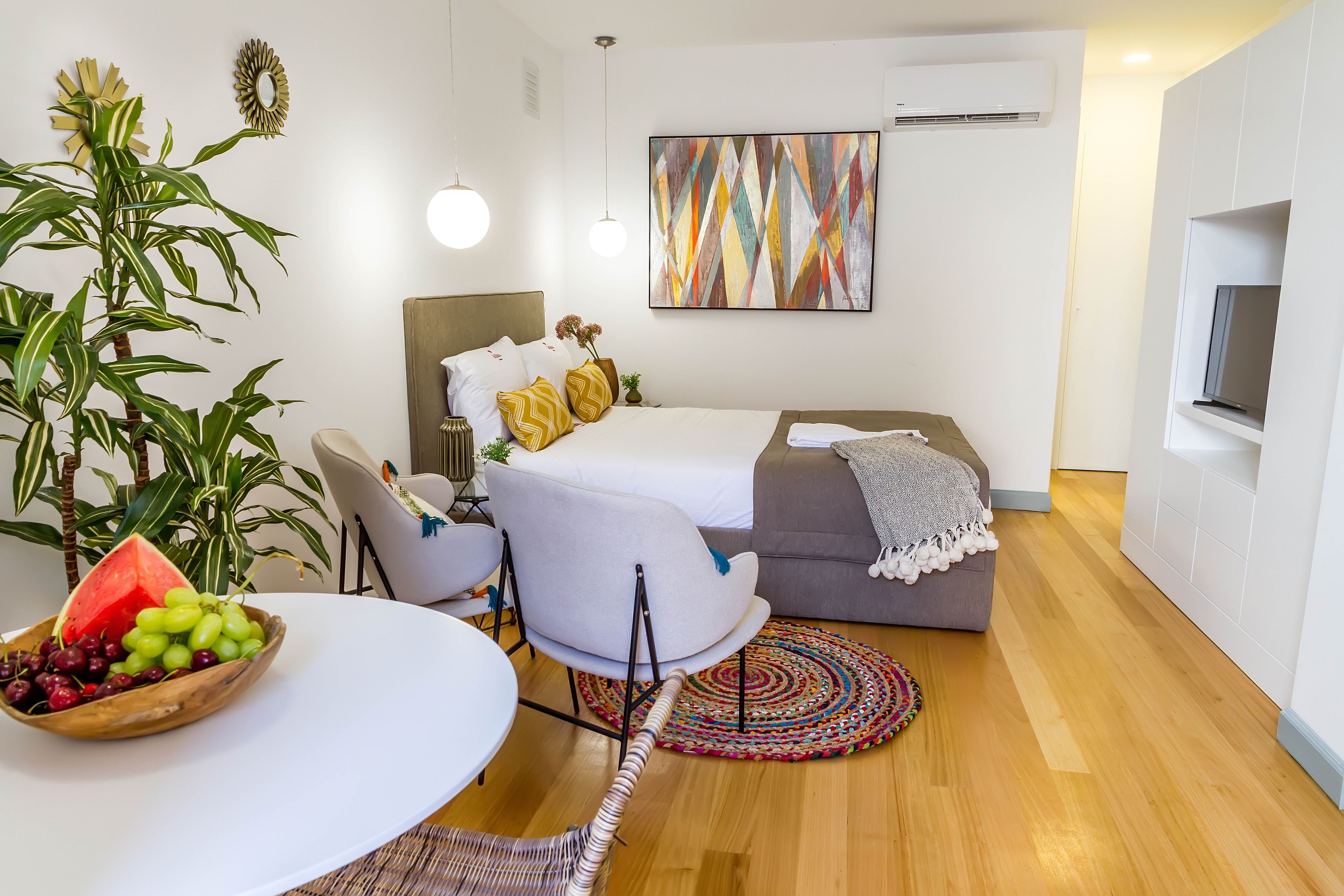 Un dormitorio moderno con cama, mesita de noche y una zona de comedor con frutero.