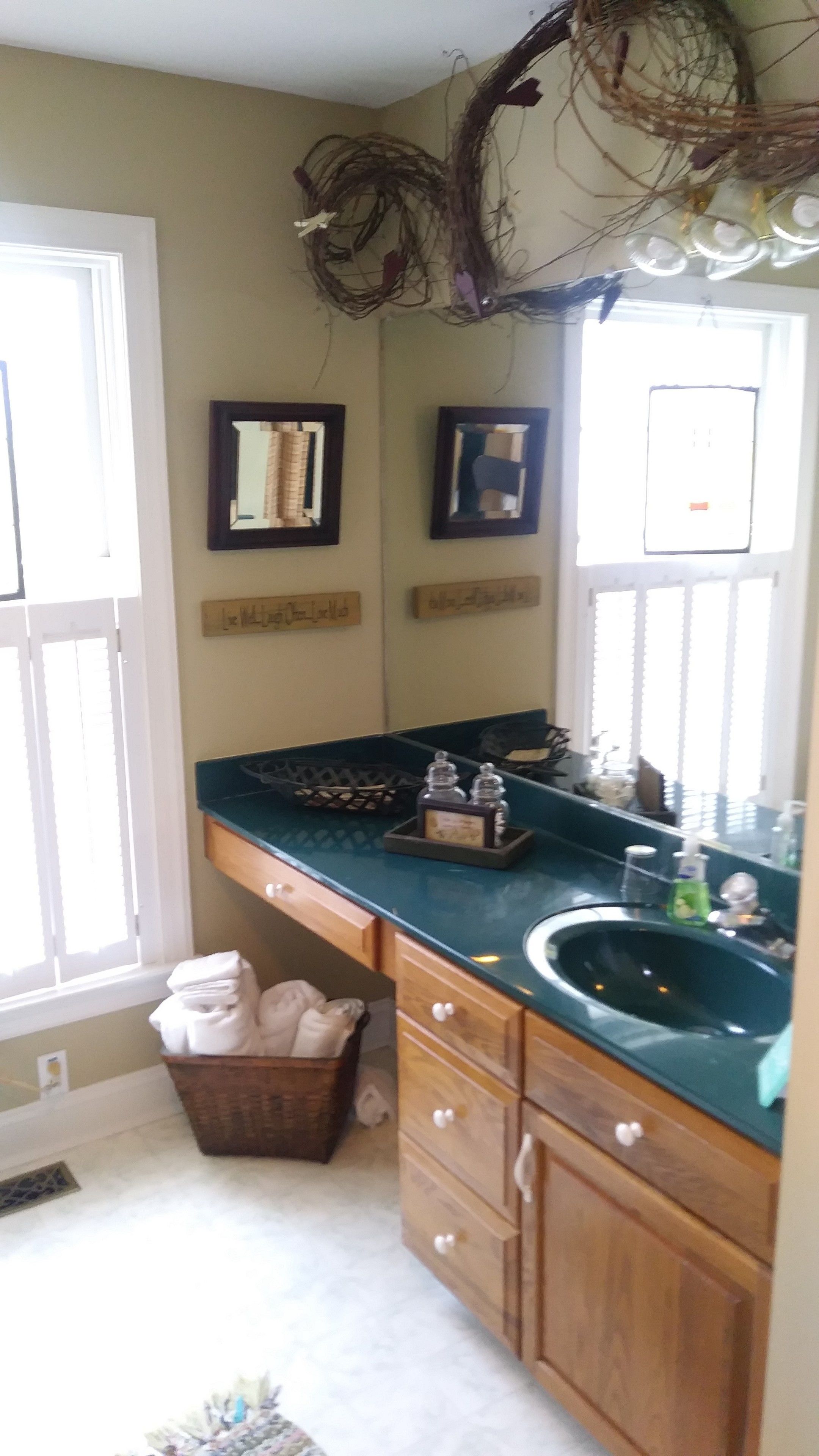 A kitchen with a green countertop, wooden cabinets, a sink, and a window with blinds.