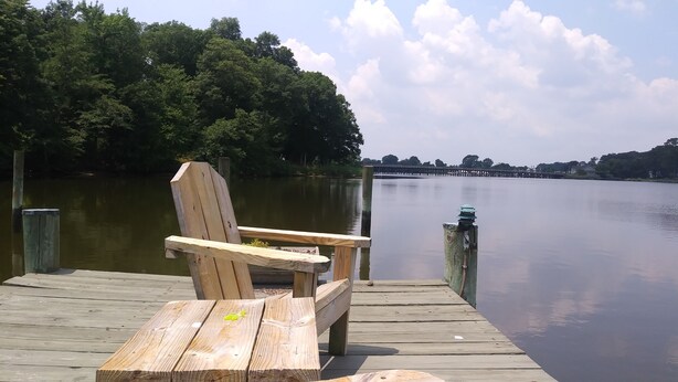 A wooden dock with a bench and a wooden post with a light fixture. - Marvel's on the Creek (East New Market)