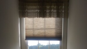 A corner room with a window overlooking a green field, a wooden barrel, a chair, and a small table with a candle and flowers. - Marvel's on the Creek (East New Market)
