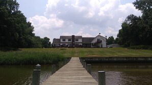 A wooden dock leading to a house with a lawn and a pond. - Marvel's on the Creek (East New Market)