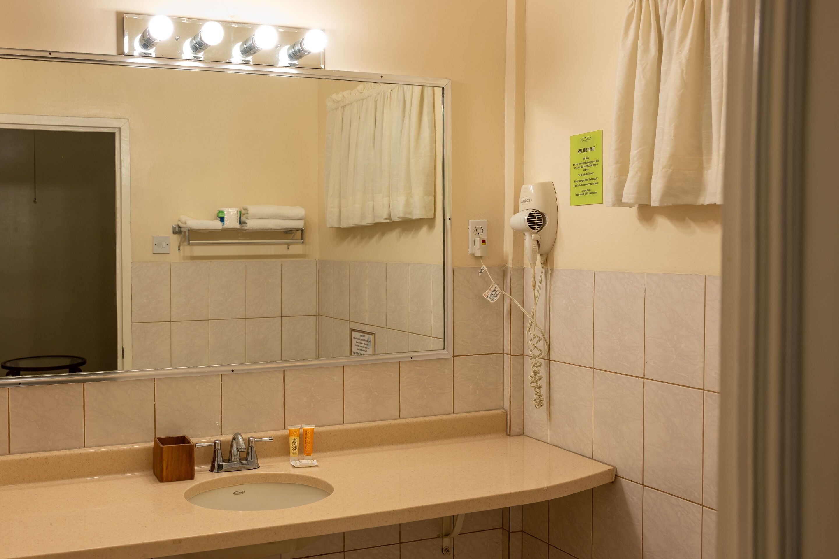 A bathroom with a sink, mirror, towel rack, and a hairdryer.