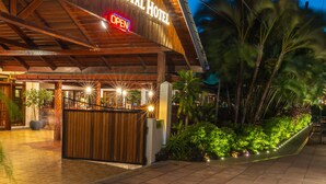 La façade extérieure du Grand Coastal Hotel, avec son revêtement en bois et une enseigne indiquant « Ouvert ».