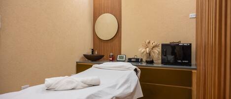 A room with a bed, a round mirror, a bowl, a towel, a towel warmer, and a small plant.