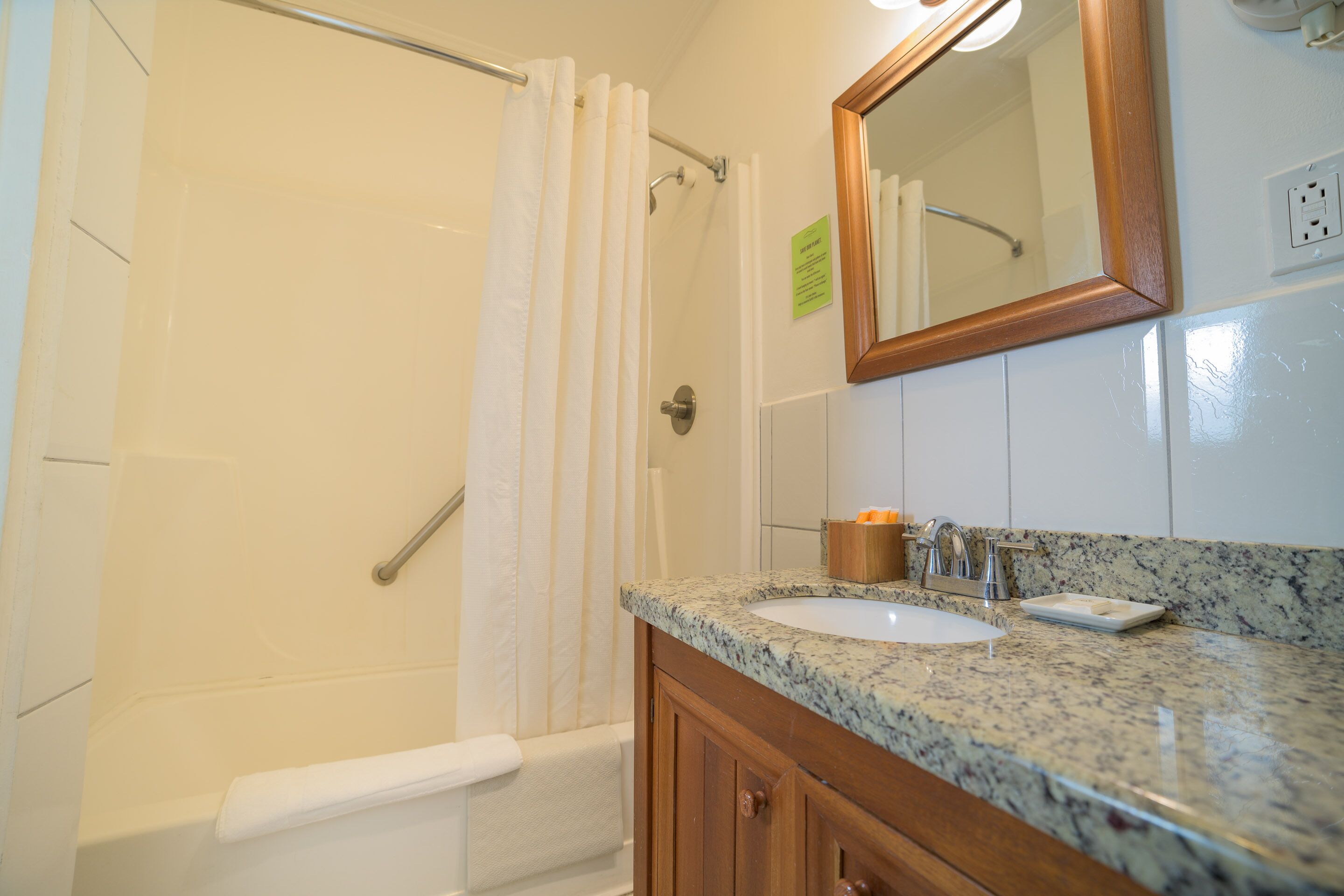 A bathroom with a shower, a sink, and a mirror.