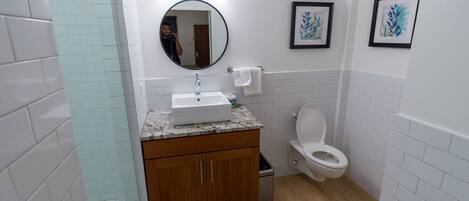 Een badkamer met een wastafel, spiegel, toilet en houten kastjes.