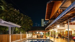 Une piscine avec une terrasse en bois, un espace extérieur aménagé pour s’asseoir et un coin restaurant.