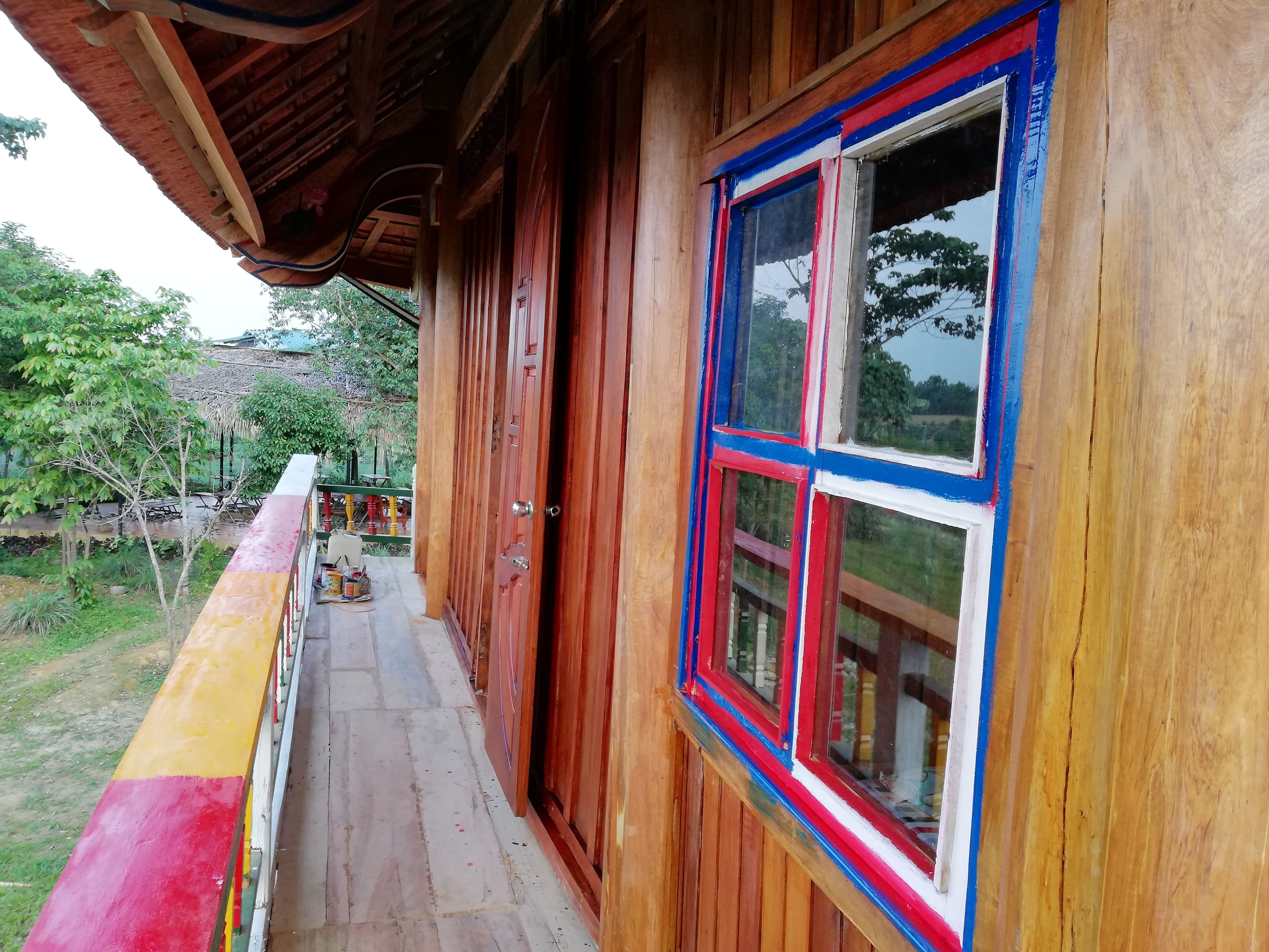 A wooden building with a balcony and a large window with red, white, and blue trim.