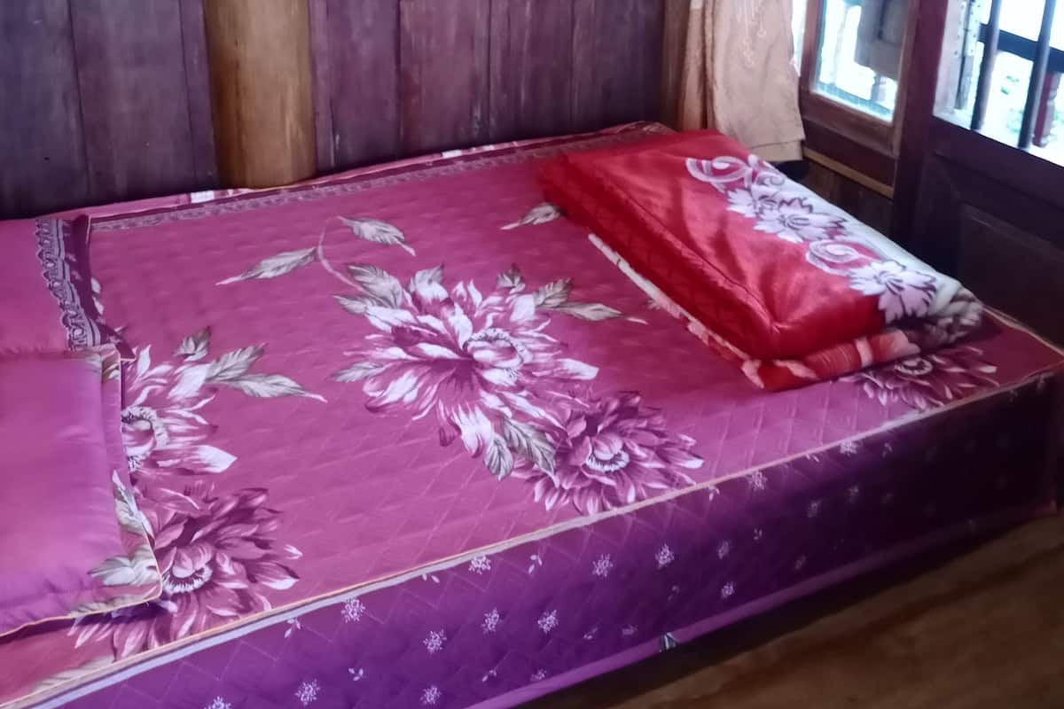 Ein Zimmer mit Holzboden und einem Bett mit floralem Bettbezug.