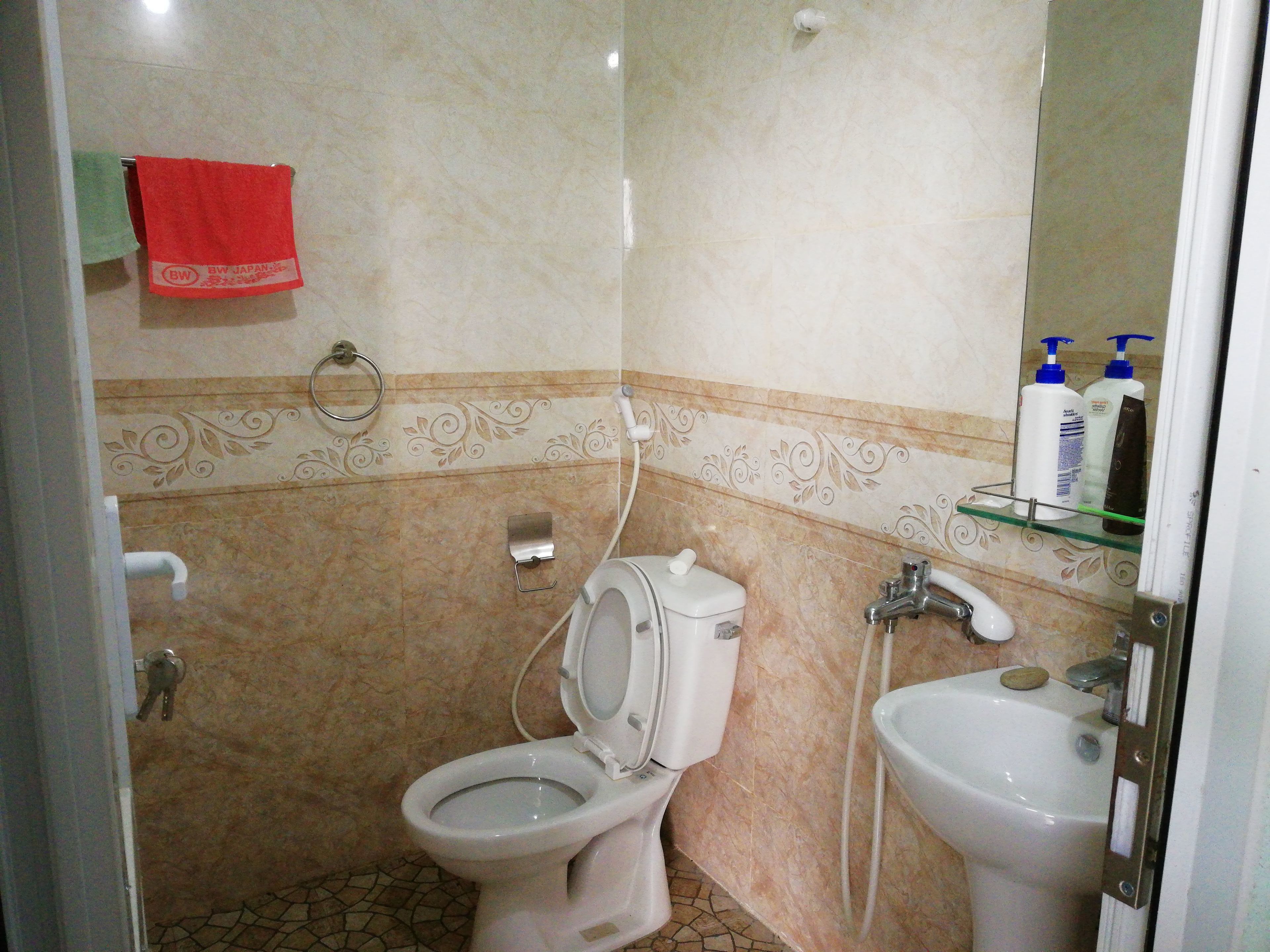 Et badeværelse med toilet, vask og dekorative vægfliser.