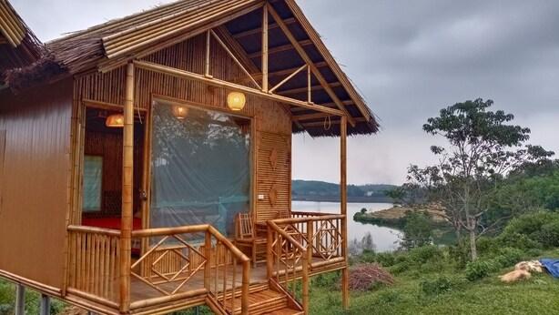 Une cabane en bois dotée d’un balcon, d’une grande fenêtre et offrant une vue sur un lac.