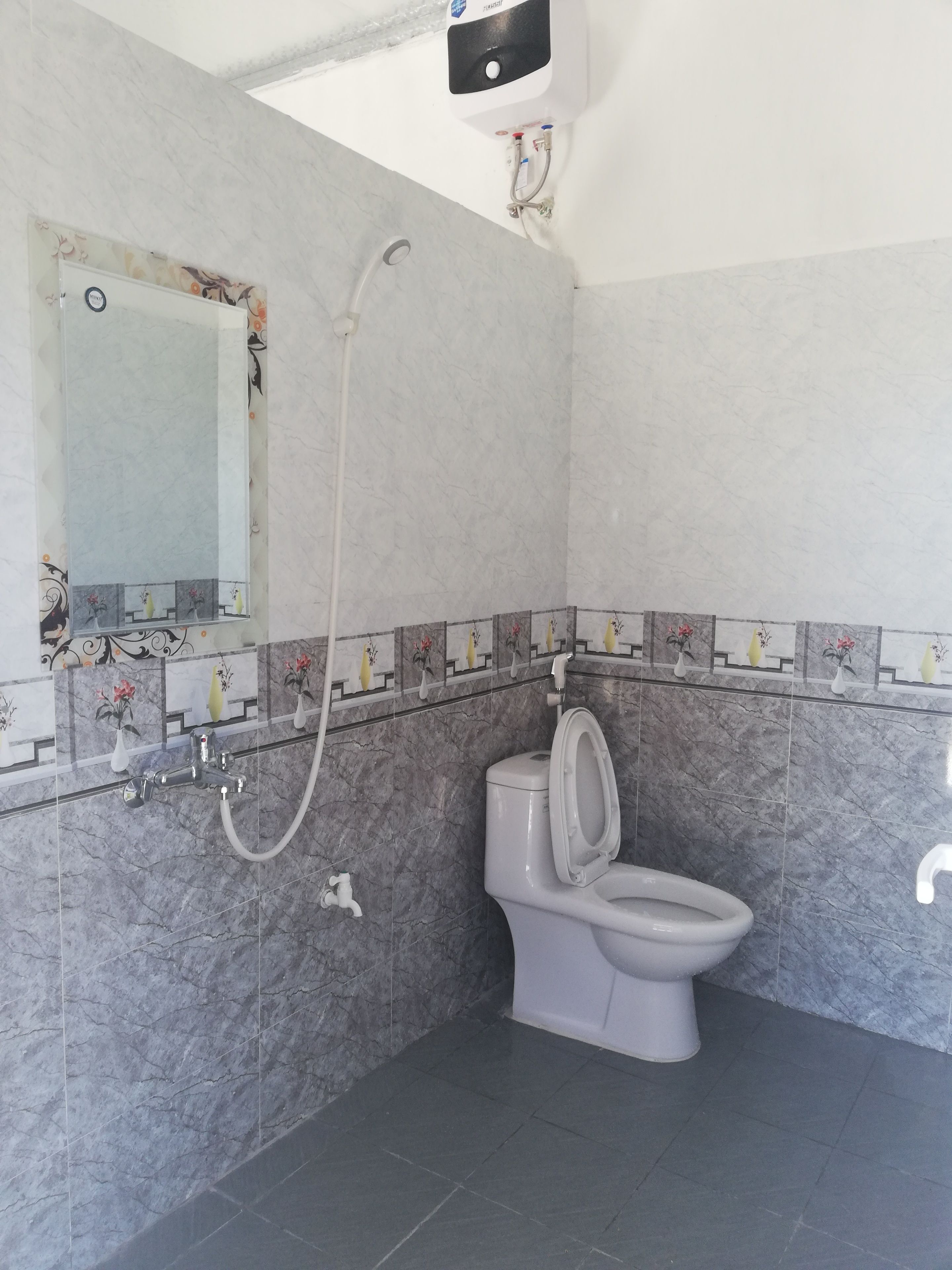Un baño con inodoro, ducha y espejo.