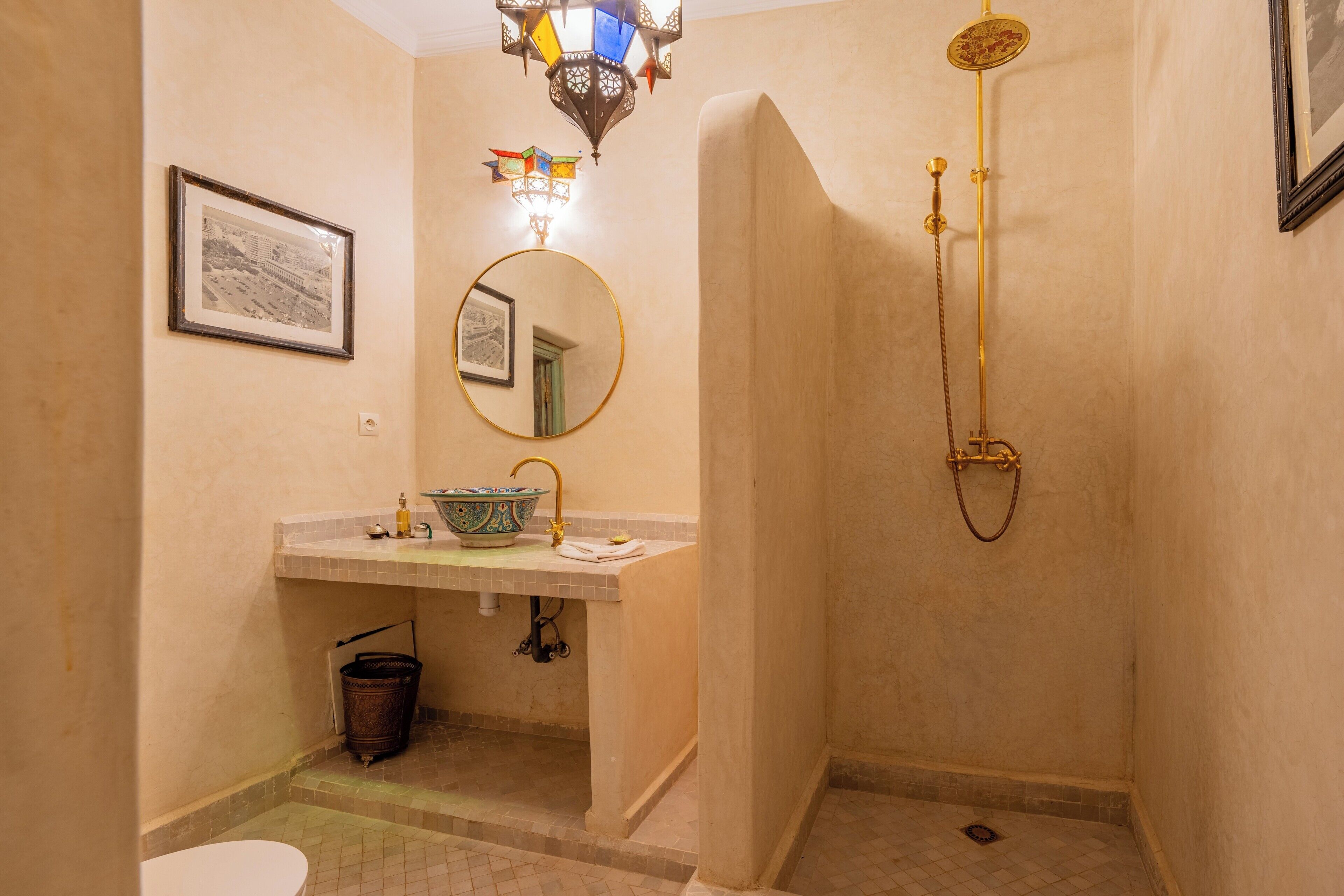 A bathroom with a sink, mirror, shower, and a framed picture on the wall.