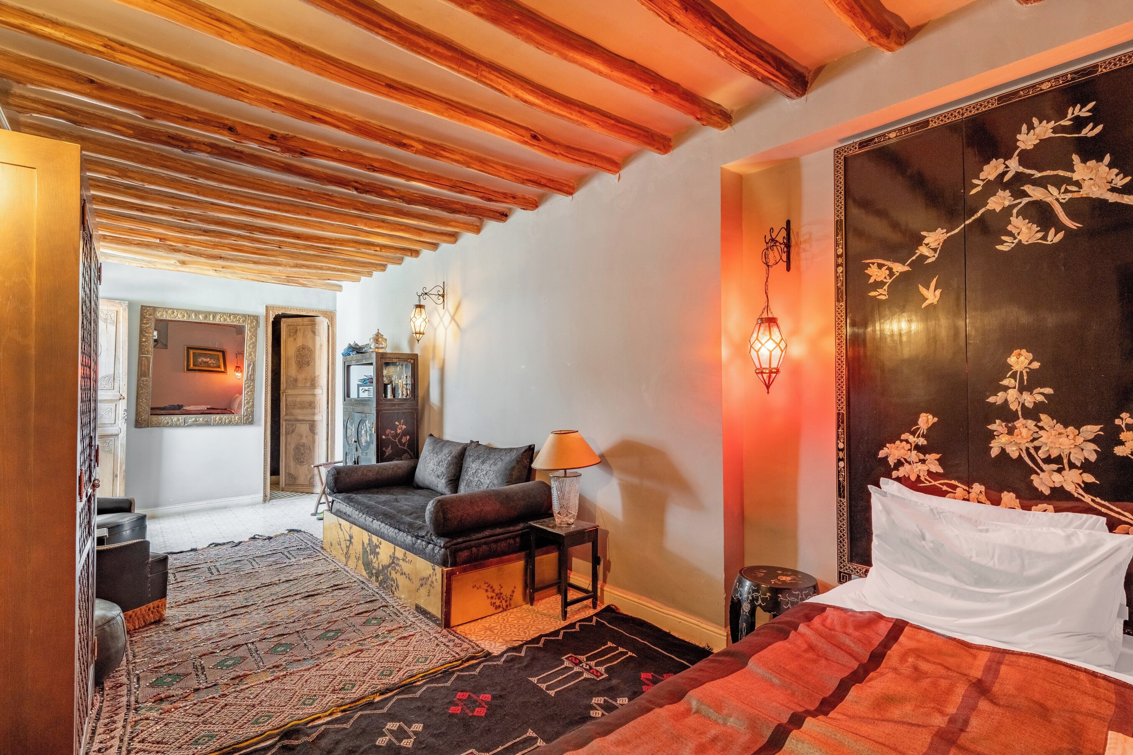 A cozy room with a sofa, a bed, and a decorative wall panel.