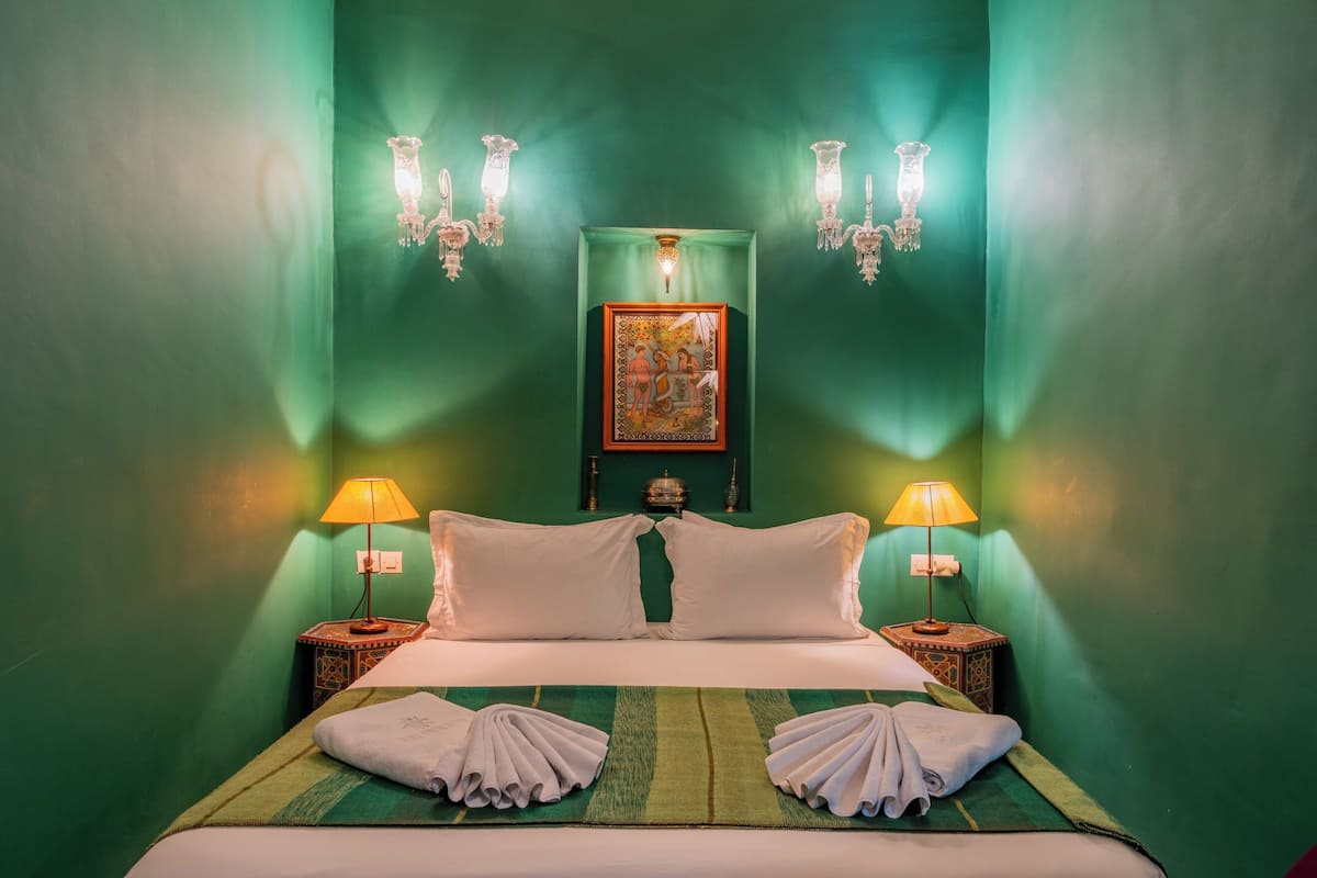 A neatly made bed with white linens, two bedside lamps, and a framed artwork above the bed.