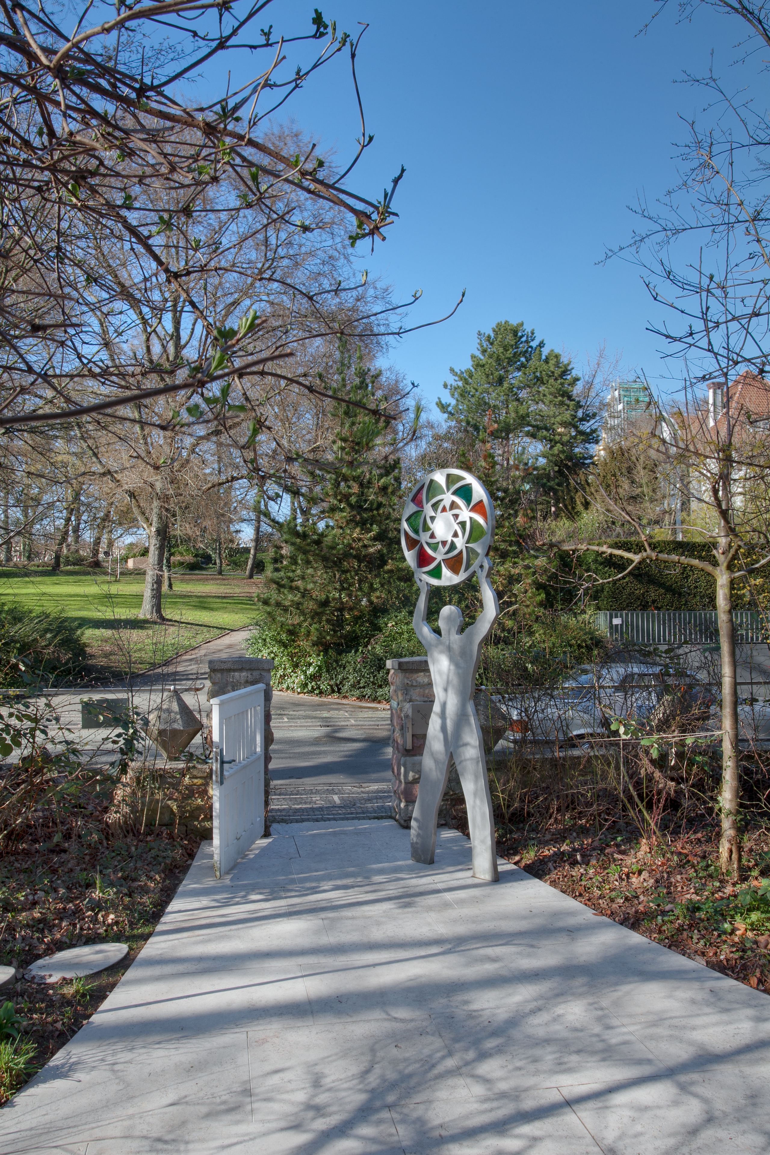 A pathway with a sculpture of a figure holding a circular object.