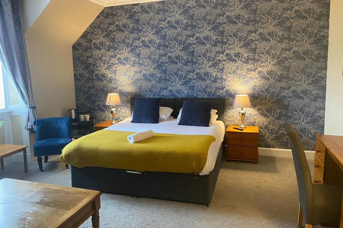 Une chambre à coucher comprenant un lit, deux tables de chevet avec des lampes, une chaise et un bureau.