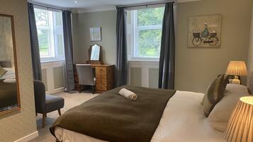 Un dormitorio con cama, escritorio, silla y ventana con cortinas.