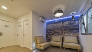 A hotel room with a cityscape mural, a sofa, a chair, and a ceiling light. - Hotel Ciudad del Mar (Las Palmas de Gran Canaria)