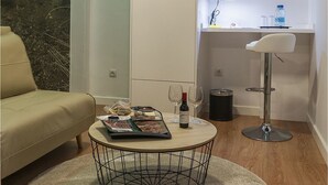 A modern living room with a round coffee table, a beige sofa, a wall-mounted TV, and a kitchen area with a sink and a bar stool. - Hotel Ciudad del Mar (Las Palmas de Gran Canaria)